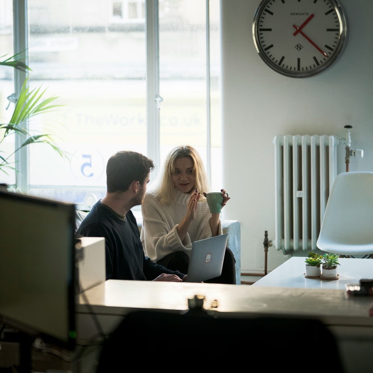 Two colleagues collaborating on a laptop in a modern office