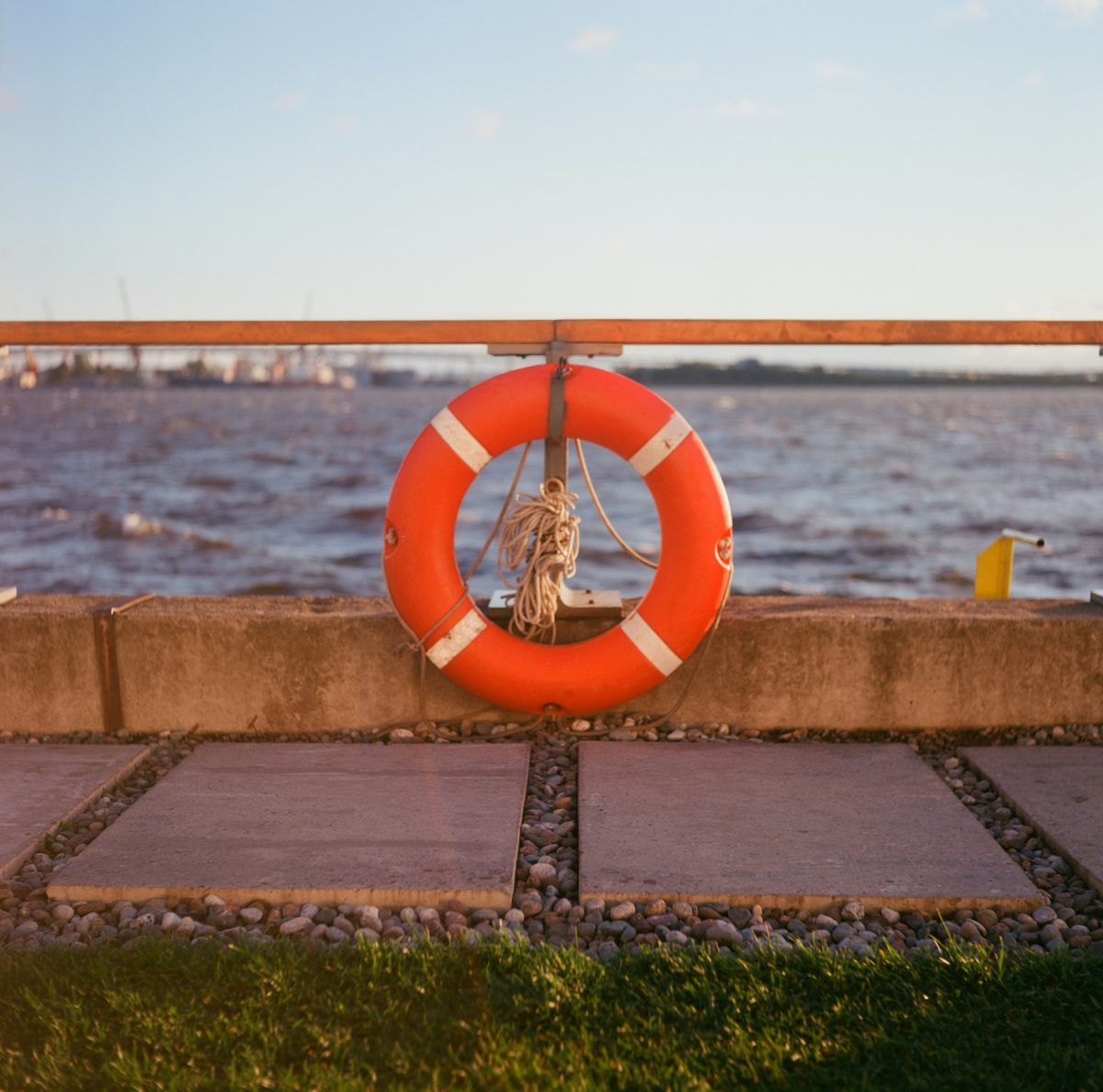 Orange life ring on a waterfront railing at sunset, symbolizing rescue and recovery